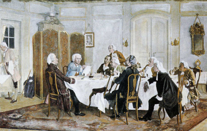 Filósofo Kant sentado a la mesa con varios amigos
