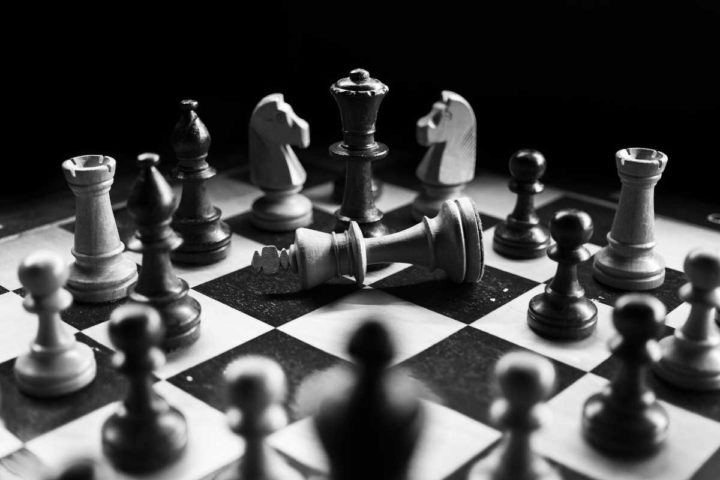 Tablero de ajedrez en blanco y negro, con piezas alrededor del Rey caído