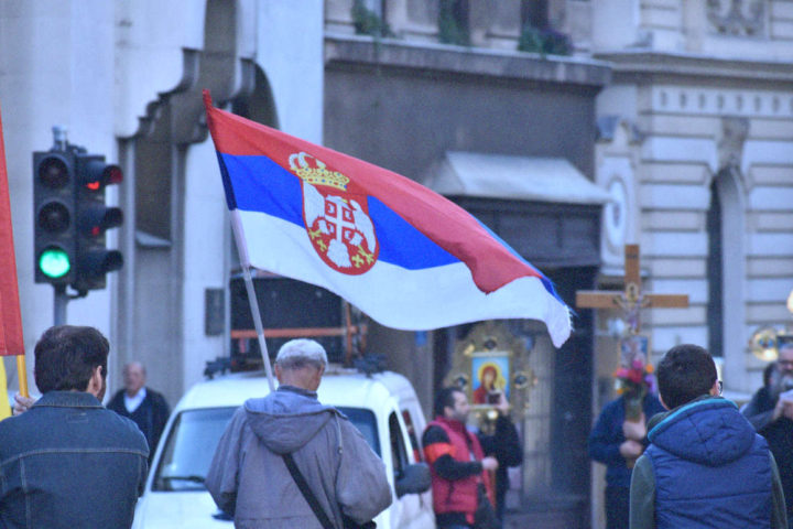 Hombre marcha con bandera serbia en manifestación religiosa