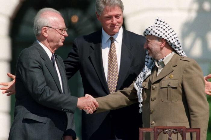 El Presidente de EE.UU. Bill Clinton (C) se encuentra entre el líder de la OLP Yasser Arafat (D) y el Primer Ministro israelí Yitzahk Rabin (I) mientras se dan la mano por primera vez, el 13 de septiembre de 1993 en la Casa Blanca en Washington DC, después de firmar los Acuerdos de Oslo Israel-OLP sobre la autonomía palestina en los territorios ocupados. / FOTO AFP / J. DAVID AKE