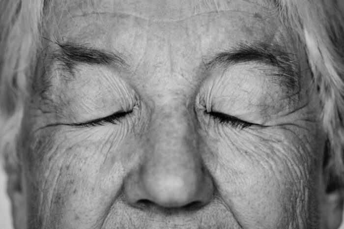 Rostro de una anciana con los ojos cerrados, foto en blanco y negro.